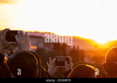 Gros plan de téléphones portables et de caméras parmi une foule de touristes à Piazzale Michelangelo dans le centre de Florence en Toscane, Italie au coucher du soleil. Banque D'Images