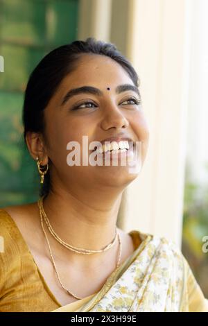 Jeune femme indienne portant des vêtements traditionnels, souriant à la maison Banque D'Images