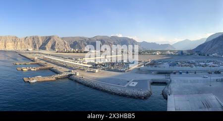 Khasab, Oman - 1er janvier 2024 : le soleil de l'heure d'or projette une lueur chaude sur le port de Khasab, mettant en évidence les eaux sereines, les zones d'amarrage animées et le Banque D'Images