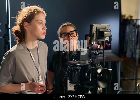 Portrait de taille haute de deux réalisatrices utilisant un appareil photo numérique sur le plateau ensemble Banque D'Images
