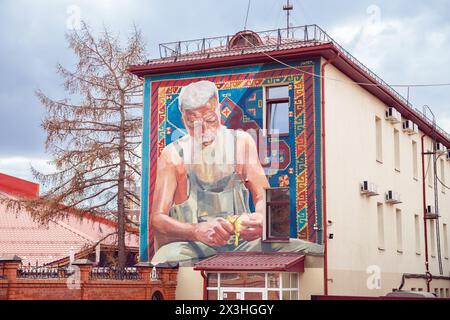 Murale réaliste avec homme serbe senior gris barbu pelant pomme avec couteau sur tapis par l'artiste Wuper KEC. Portrait plein mur de la maison 56A sur Malysh Banque D'Images