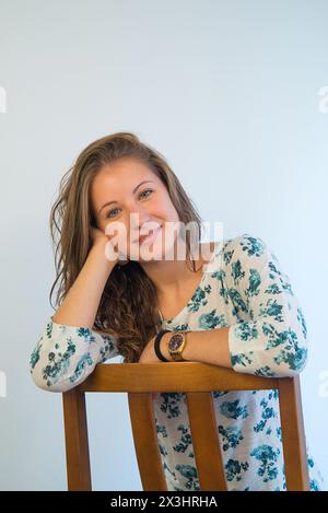 Jeune femme assise à cheval, souriante, tête sur la main. Banque D'Images