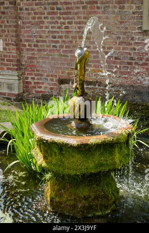 Ancienne fontaine couverte de mousse avec une sculpture en bronze dans un environnement de jardin serein Banque D'Images