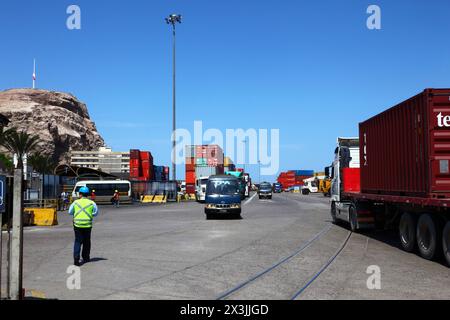 Camion porte-conteneurs entrant dans le port, conteneurs empilés en arrière-plan, pointe El Morro sur le côté gauche, Arica, Chili Banque D'Images