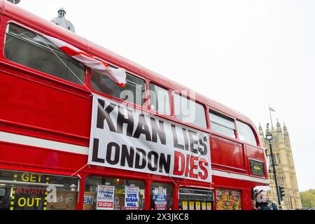 Londres, Royaume-Uni. 27 APR, 2024. Le bus passe devant Trafalgar Square avec un panneau qui indique "Khan lie Londres meurt" L'autocar avait également d'autres marques contre Khan et ULEZ, des activistes étaient à bord. Crédit Milo Chandler/Alamy Live News Banque D'Images