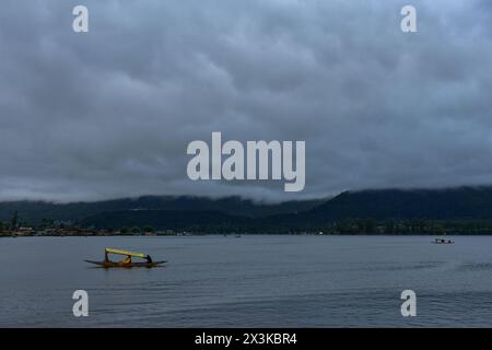 Srinagar, Inde. 27 avril 2024. Un batelier cachemirien ramène son bateau à travers le célèbre lac Dal après une forte pluie à Srinagar. De fortes précipitations sont attendues dans la plupart des endroits du Jammu-et-Cachemire au cours des prochaines 48h. Des chutes de neige modérées à fortes sont également attendues sur les tronçons plus élevés de la vallée. (Crédit image : © Saqib Majeed/SOPA images via ZUMA Press Wire) USAGE ÉDITORIAL SEULEMENT! Non destiné à UN USAGE commercial ! Crédit : ZUMA Press, Inc/Alamy Live News Banque D'Images