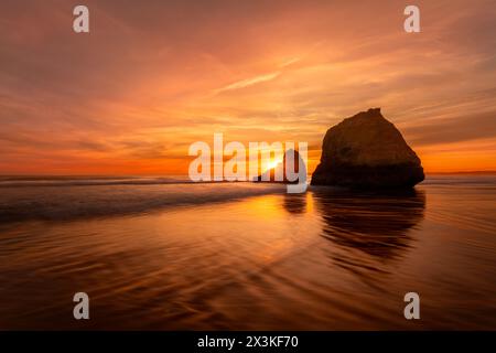 Coucher de soleil sur Praia dos Três Irmãos à Alvor, Algarve, Portugal avec le soleil derrière les célèbres rochers Banque D'Images