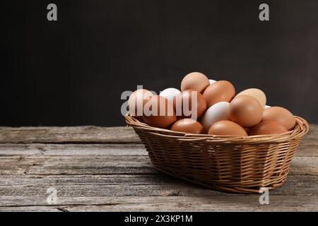 Oeufs de poule frais dans un panier en osier sur une table en bois. Espace pour le texte Banque D'Images