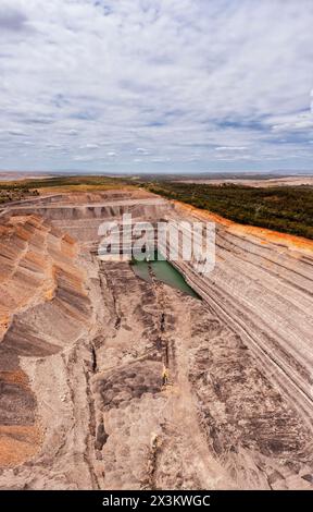 Énorme mine de minerai de fer noir à ciel ouvert dans Hunter Valley en Australie - panorama vertical aérien. Banque D'Images