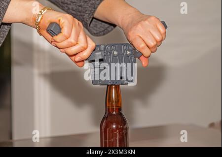 Femme utilisant un bouchon pour attacher des couvercles métalliques aux bouteilles de bière. Banque D'Images