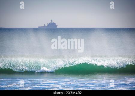 Le surf de l'océan Pacifique roule, tandis qu'un navire de la marine est assis à l'horizon lointain, à Coronado, en Californie. Banque D'Images