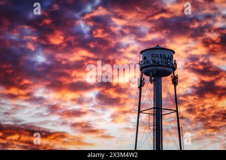 Le soleil d'hiver se couche sur la route 66 derrière le château d'eau à Shamrock, Texas. Banque D'Images