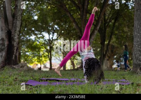 Fille latino-américaine s'amusant dans le parc faisant des exercices de gymnastique avec dextérité. Banque D'Images