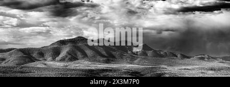 Une chaîne de montagnes lointaine près de Glenwood, NM. Une petite formation de roches blanches pointues apparaît juste à droite du centre du cadre. Beaucoup de nuages et de désert Banque D'Images