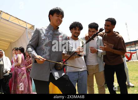 Le Caire, Égypte. 27 avril 2024. Les étudiants égyptiens profitent d'un instrument de musique chinois traditionnel lors d'une cérémonie pour célébrer la Journée de la langue chinoise au Caire, en Égypte, le 27 avril 2024. Les étudiants qui étudient dans les collèges égyptiens ont célébré samedi la Journée de la langue chinoise des Nations Unies avec un événement thématique comprenant un concert, une dégustation de nourriture et de thé, une comédie de sketchs et une exposition d'art. POUR ALLER AVEC 'Feature : égyptiens, étudiants chinois marquent la Journée de la langue chinoise des Nations Unies au Caire' crédit : Ahmed Gomaa/Xinhua/Alamy Live News Banque D'Images