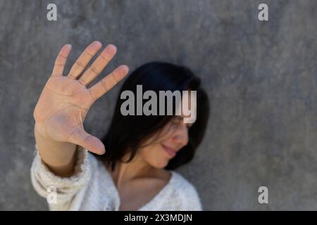 Femme adulte d'Amérique latine (29) étend la paume de sa main devant elle comme un signe d'arrêt, tout en tournant sa tête sur le côté comme un signe de ne pas wanti Banque D'Images