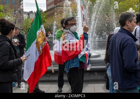 New York, États-Unis. 27 avril 2024. Un manifestant tient des pancartes et des drapeaux lors d'une manifestation en solidarité avec le rappeur iranien Toomaj Salehi, condamné à mort par les tribunaux iraniens pour avoir soutenu un mouvement de protestation antigouvernemental à Washington Square Park. Crédit : SOPA images Limited/Alamy Live News Banque D'Images