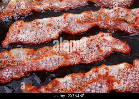 Bacon frit dans une poêle sur fond Banque D'Images