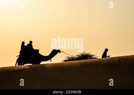 Silhouette de chameau avec deux personnes assises dessus traversant les dunes de sable à Sam Jaisalmer Rajasthan Inde Banque D'Images