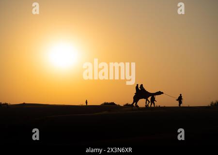 Silhouette de chameau avec deux personnes assises dessus traversant les dunes de sable à Sam Jaisalmer Rajasthan Inde Banque D'Images