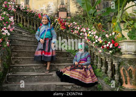 Fleurs des femmes hmong assises sur les escaliers du palais des rois Hmong (Vau Meo) à bac Ha, province de Lao Cai, Vietnam Banque D'Images