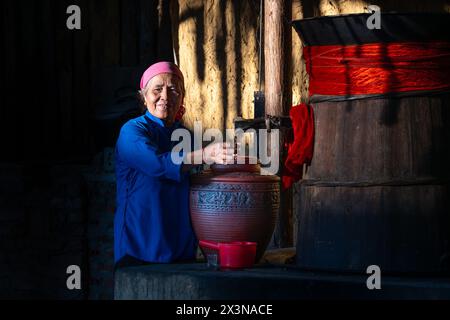 Femme hmong versant du vin de riz d'un tonneau, bac Ha, province de Lao Cai, Vietnam Banque D'Images