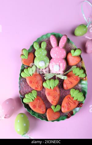 Biscuits de pain d'épice de Pâques en forme de lapin et de carottes sur fond rose. Carte de voeux de Pâques. Vue de dessus Banque D'Images