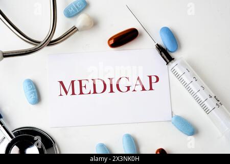 Concept médical. MEDIGAP sur la carte près du stéthoscope, pilules, seringue sur fond blanc Banque D'Images