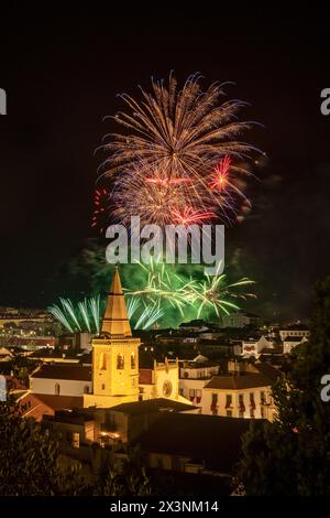 Feux d'artifice nocturnes à la Festa dos Tabuleiros à Tomar, Portugal, avec la tour de l'église São João Baptista à l'honneur. Banque D'Images