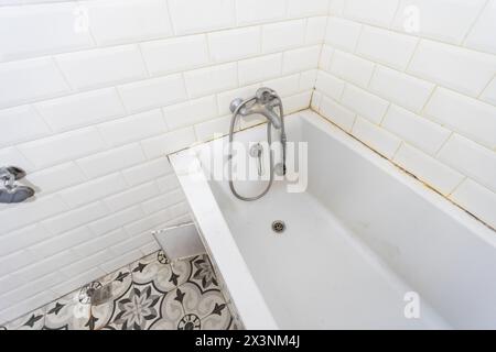 Intérieur des toilettes étroites avec toilettes murales avec murs blancs et sol en damier Banque D'Images