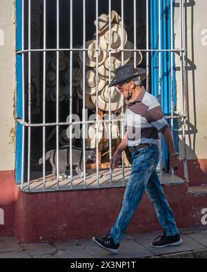 Un homme portant un chapeau passant devant la fenêtre d'un magasin de chapeaux dans la vieille ville, Trinidad, Cuba Banque D'Images