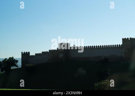 Panorama rétroéclairé contre le ciel bleu du mur de la nécropole médiévale fortifiée de Chellah à Rabat, Maroc. Un historique et archéologique Banque D'Images