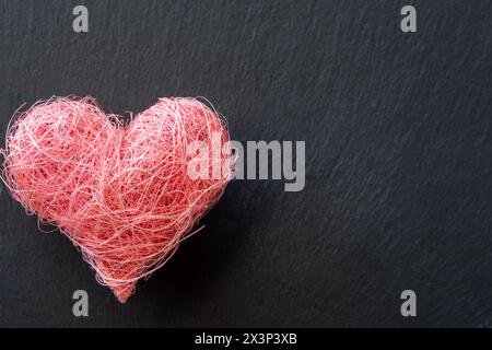 Forme de coeur en tissu matériel sur le fond noir avec copyspace. Concept de Saint Valentin et amour romantique Banque D'Images