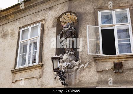 Vienne, Autriche. Statue votive et ancien lampadaire entre deux fenêtres, sur la façade d'un ancien bâtiment de la rue Griechengasse, dans l'historica Banque D'Images