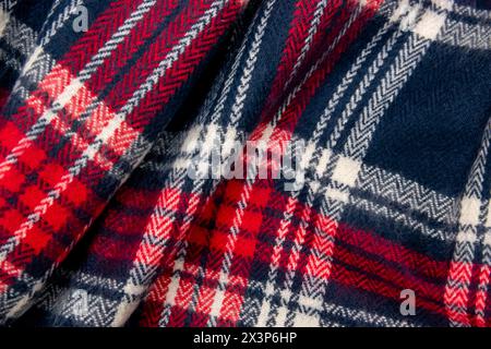Tissu de texture cage bleu, blanc, rouge. Foulard hivernal en cachemire. Fond de tissu tricoté foncé chaud textile. Banque D'Images