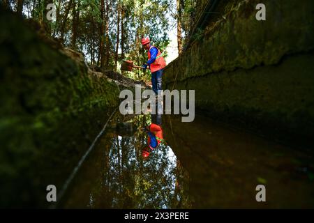 (240428) -- BIJIE, 28 avril 2024 (Xinhua) -- Un membre d'une équipe d'entretien du canal nettoie un canal sur les falaises dans le canton de Shengji dans la ville de Bijie, province du Guizhou, au sud-ouest de la Chine, 25 avril 2024. Sur les falaises abruptes, il y a plusieurs canaux qui fournissent de l'eau pour les terres agricoles voisines dans le canton de Shengji. L'une des tâches quotidiennes des membres de l'équipe d'entretien des canaux consiste à dégager les branches fanées et les pierres tombées des canaux. Dans le canton de Shengji, c'est une forme de relief karstique typique. L'eau de pluie imprègne rapidement les collines et les terrains après être tombée du ciel, dont peu peut être faible Banque D'Images