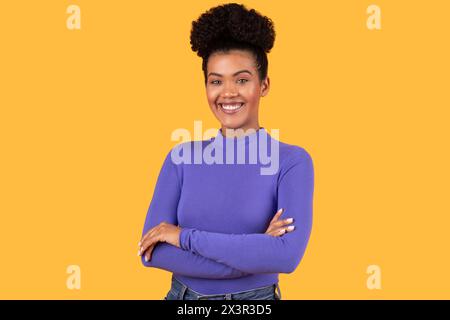 Femme souriante avec les bras croisés posant sur jaune Banque D'Images