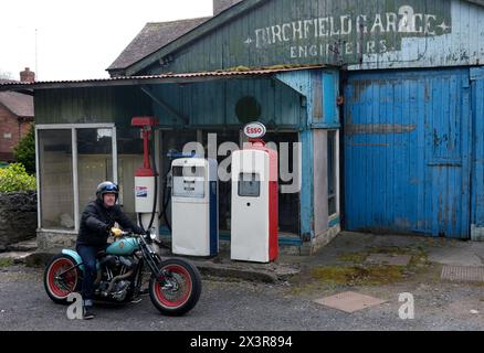 Motocycliste sur une moto construite sur mesure dans un vieux garage désaffecté à Much Wenlock, Shropshire Banque D'Images