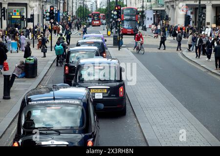Les taxis noirs de circulation font la queue et les piétons de l'arrière derrière sur Oxford Street à Londres Angleterre Royaume-Uni 2024 KATHY DEWITT Banque D'Images