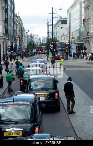 Trafic les taxis noirs font la queue et les piétons de l'arrière derrière dans la rue à Londres Angleterre Royaume-Uni 2024 KATHY DEWITT Banque D'Images