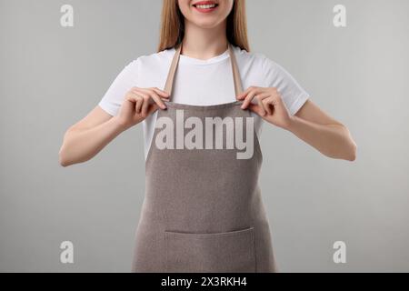 Femme portant tablier de cuisine sur fond gris, gros plan. Maquette pour le design Banque D'Images