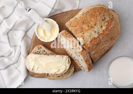 Pain savoureux avec du beurre, couteau et lait dans le verre sur la table grise, plat Banque D'Images