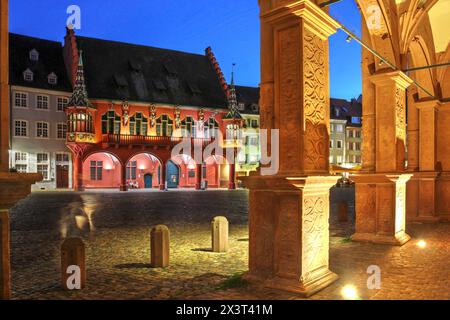 Scène de nuit sur la place Minster, Freiburg im Breisgau, Allemagne captivant la salle rouge frappante des marchands historiques (Historisches Kaufhaus). Banque D'Images