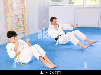 Garçon adolescent et homme d'âge moyen entraînant des coups de poing couchés en position de presse Banque D'Images