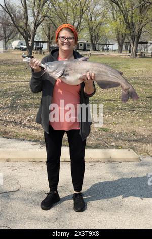 Fière femme caucasienne de 60 ans tenant un poisson-chat bleu de 12 livres, Ictclurus furcatus, pour exposer sa prise dans un lac. Banque D'Images