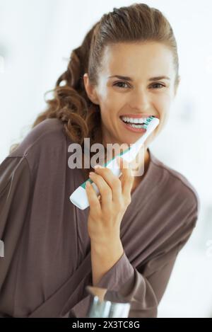 Happy young woman se brosser les dents dans la salle de bains Banque D'Images