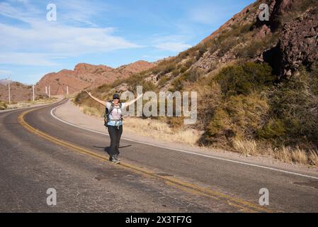 Femme randonneur ouvrant les bras au milieu de la route, insouciante, heureuse, vivant une aventure pendant ses vacances dans les montagnes de Potrerillos, hommes Banque D'Images