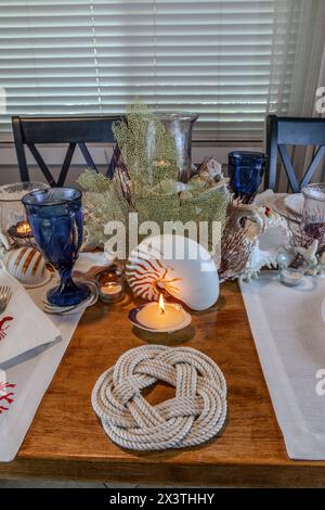 Décoration coquillage et bougie sur une table nautique avec des couleurs naturelles et un bleu profond. Banque D'Images