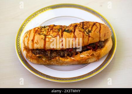 Délicieux hot dog de poulet avec sauce tomate sur une assiette blanche sur fond de bois Banque D'Images