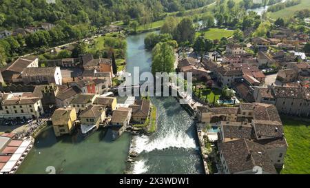 Beau village sur la rive de la rivière vue aérienne du village moulin de Borghetto sul Mincio dans le sud du lac de Garde, en Vénétie, Italie. Drone footag Banque D'Images